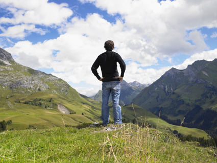 A man standing in the outdoors looking out over the Lake District, with mountains and valleys in the background