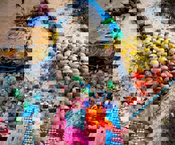 Earth Photo 2023 entry combing the sea, combing peace. Two young people lie amongst sand and plastic from the ocean.