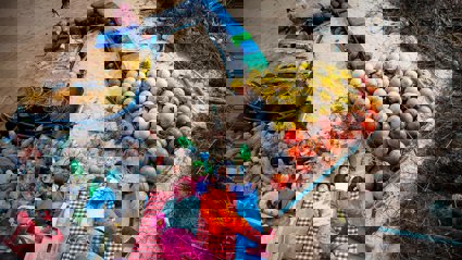 Earth Photo 2023 entry combing the sea, combing peace. Two young people lie amongst sand and plastic from the ocean.