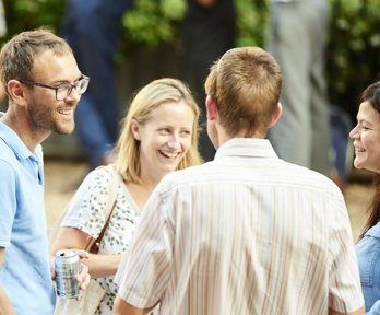 Group of four people standing in a circle chatting and smiling.