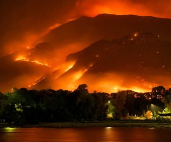 Bay at night with behind it mountains that are on fire.