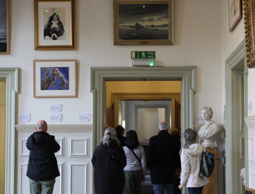 People on tour of historic building with pictures on the wall.