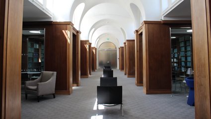 Spacious room with a variety of chairs and closed cubicles with bookcases inside.