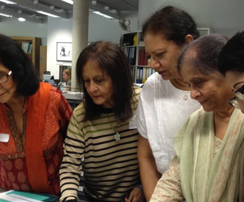 Five people looking at material displayed on a table in a library.
