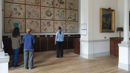 A group of people pictured from the back, viewing Hormazd Narwiella's mural in the Map Room of the Royal Geographical Society.