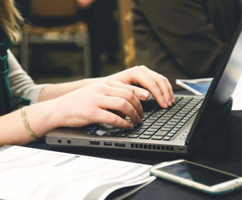 Close up of a person's hands typing on a laptop.
