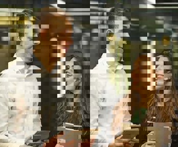 Two people in office setting in lively conversation while holding notebooks.