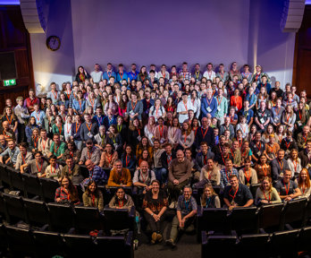 Group photo of RGS Explore 2024 attendees on the stage of the Ondaatje Theatre.
