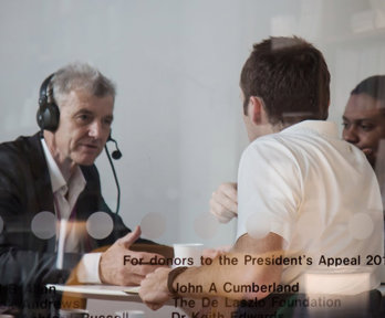 Two people interviewing a person wearing a headset.