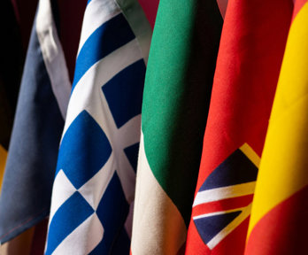 A close-up photo of five different flags positioned next to each other in a row.